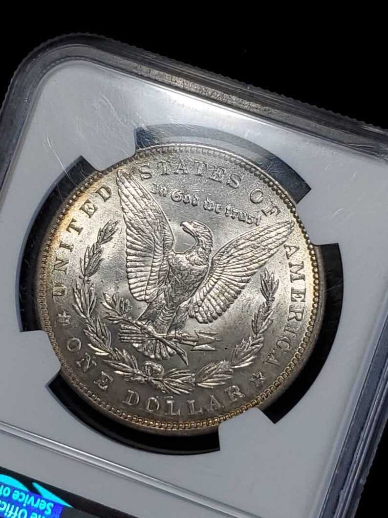1887   MS 63 Silver Morgan Dollar, NGC  MS 63  Silver Coin  Beautiful toning- small chip on top of the case -  Regular -129   Lot # 1486